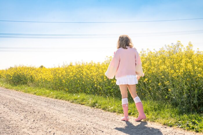 In bequemen rosa Gummistiefeln beim Spaziergang auf einem Feldweg