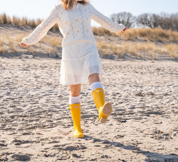 Gelbe Hunter Gummistiefel im Herbst mit warmen weißen Socken am Strand